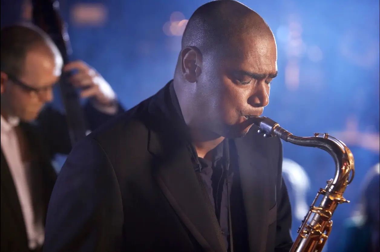 A man playing the saxophone in front of other people.